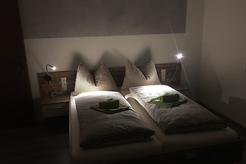Willkommen in diesem stilvollen Schlafzimmer mit bequemem Bett, Lampen und gemütlichen Kissen. Entspannen Sie sich und genießen Sie Ihren Aufenthalt!