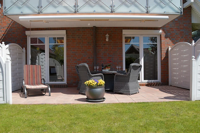 Terras met markies, rieten meubels en ligstoel.