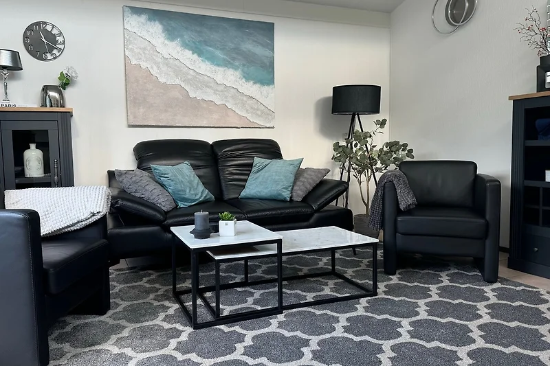 Modernes Wohnzimmer mit grauem Sofa, Holzdekor und großen Fenstern.