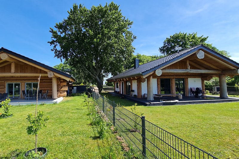 Ferienhaus mit grünem Garten, umgeben von Natur und einem blauen Himmel.