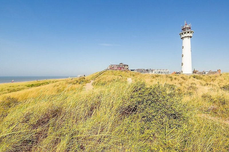 Leuchtturm mit Blick auf das Meer und eine grüne Landschaft.