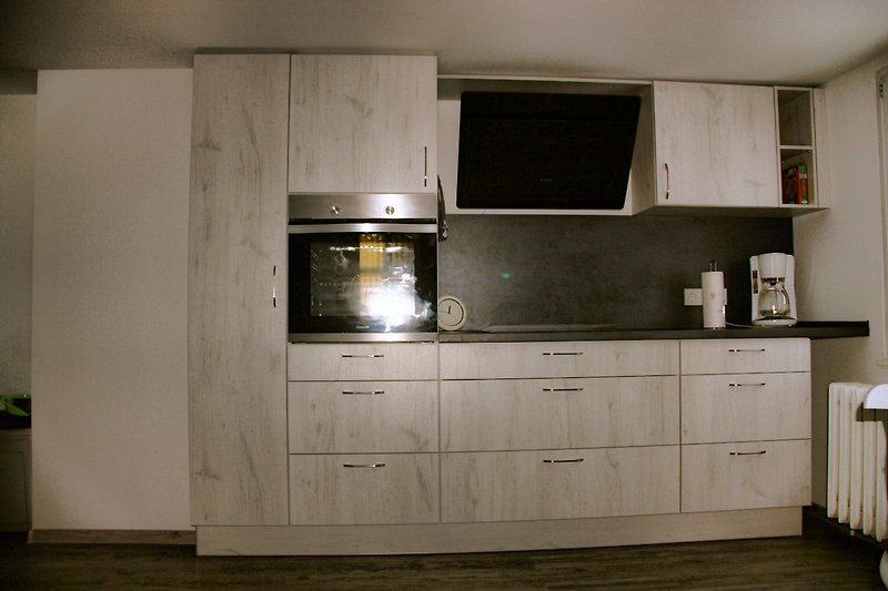 Moderne Küche mit grauen Schränken, Holztheke und Küchengeräten.