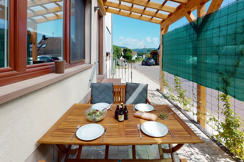 Holztisch mit Stühlen und Geschirr im Freien. Gemütliche Atmosphäre.