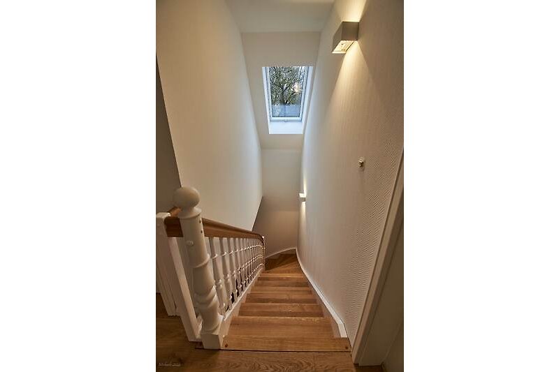 Treppe aus Holz, Fenster, Metallgeländer, Decke, Holztür.