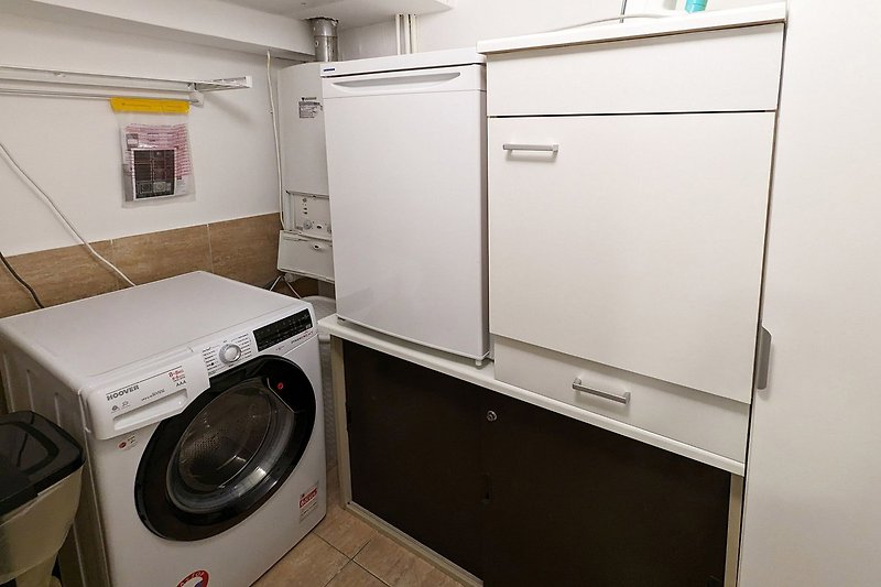 Waschküche mit Waschmaschine/Trockner, Kühlschrank und Putzschrank