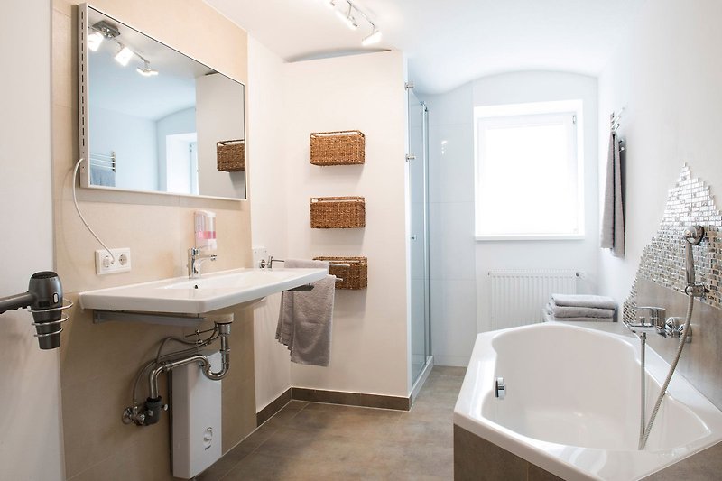 Badezimmer mit Spiegel, Waschbecken, Badewanne, Dusche und Tageslichtfenster.