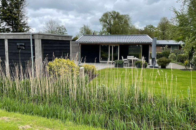 Ländliches Haus mit Garten, Bäumen und weitem Himmel.