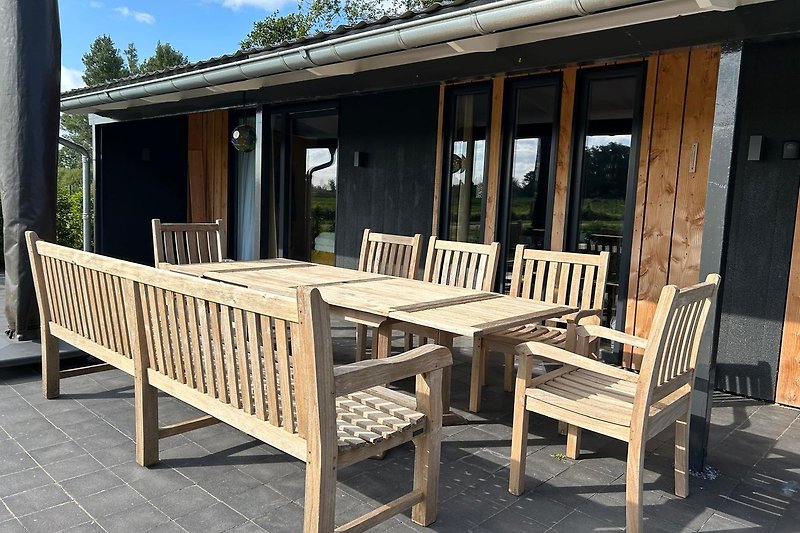 Holzveranda mit Tisch, Stühlen und Blick auf den Garten.