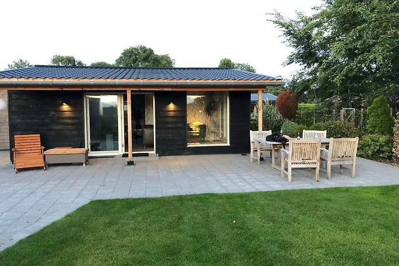 Gemütlicher Garten mit Terrasse, Tisch und Stühlen.