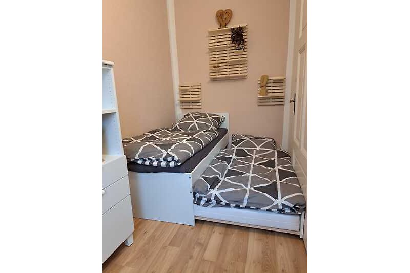 Ein gemütliches Schlafzimmer mit stilvollem Holzboden und ausziebarem Bett.