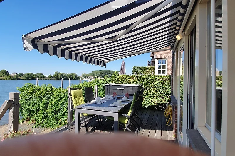 Überdachte Terrasse mit Sitzgruppe, Tisch, Pflanzen und Gartenblick.