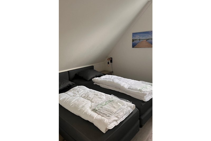 Gemütliches Schlafzimmer mit Holzbett, bequemer Matratze und stilvoller Bettwäsche.
