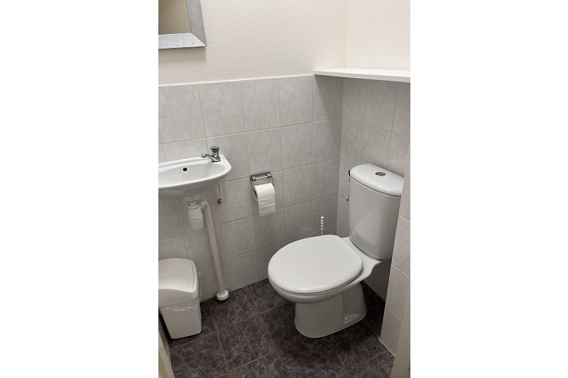 Moderne Badezimmerausstattung mit Toilette, Waschbecken und Spiegel.