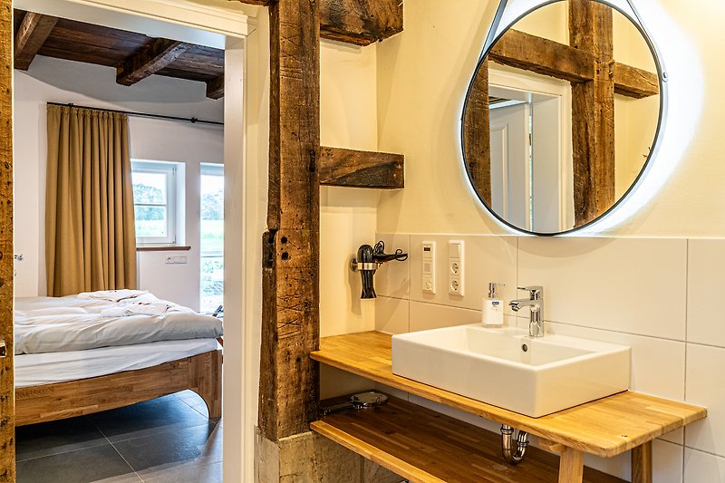 Stilvolles Badezimmer mit elegantem Spiegel, Waschbecken und modernen Armaturen.