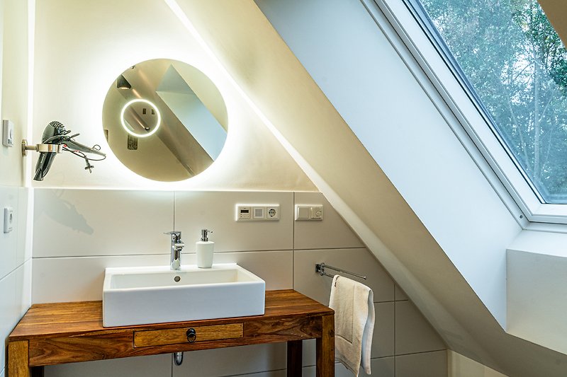 Schönes Badezimmer mit Spiegel, Waschbecken und Holzmöbeln.