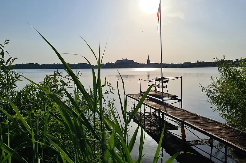 Seeufer mit Steg und ruhiger Spiegelung.