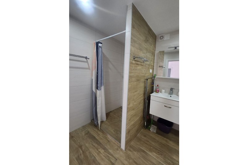 Schönes Badezimmer mit Holzboden, Waschbecken und Spiegel.