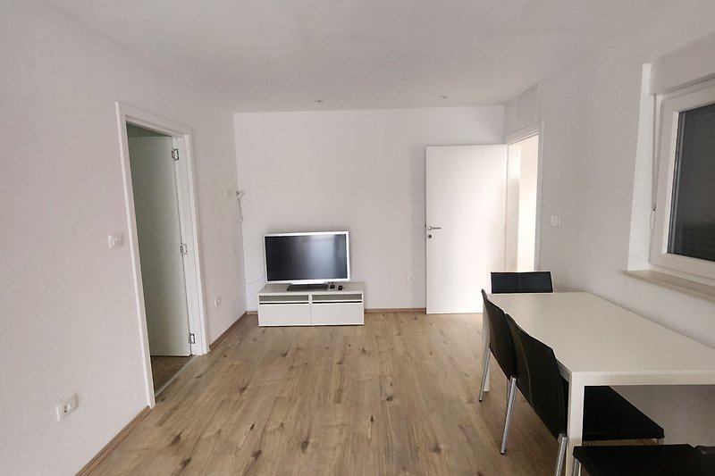 Gemütliche Wohnung mit Holzboden, Wohnzimmer und Fernseher.