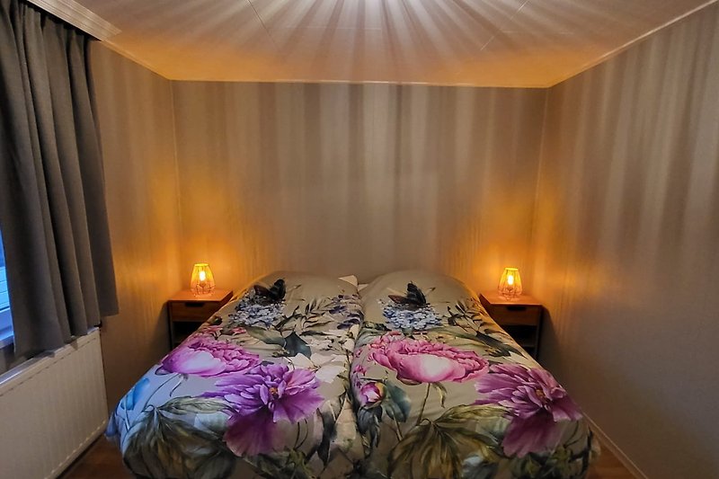 Comfortabele slaapkamer met houten bedframe en sfeervolle verlichting.