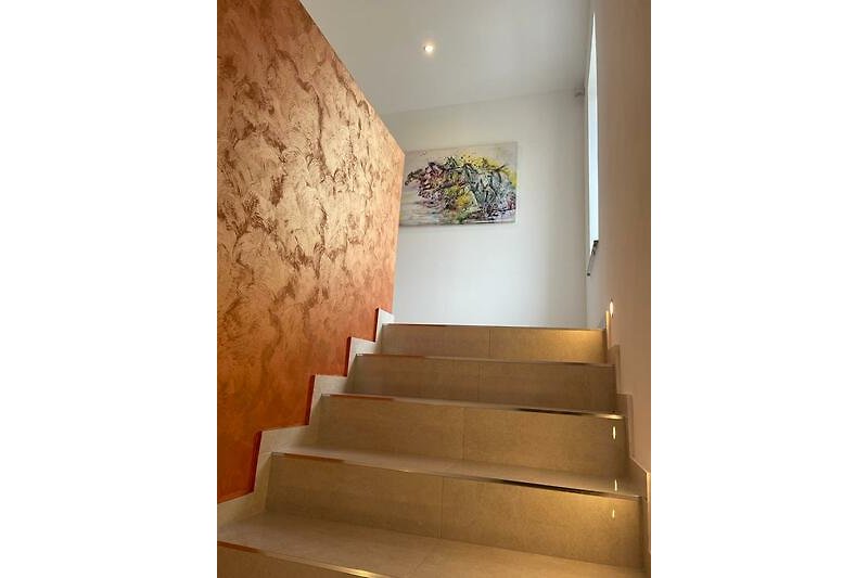 Moderan umjetnički dom s drvenim stepenicama i umjetničkim djelima.