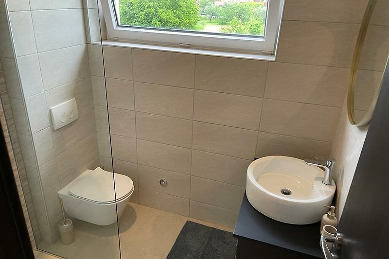 Moderan interijer kupaonice s ljubičastim detaljima i keramičkim umivaonikom.
