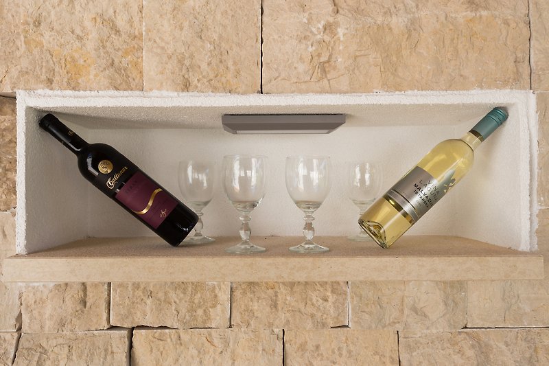 Elegant barware with wine and candles on wood wall.