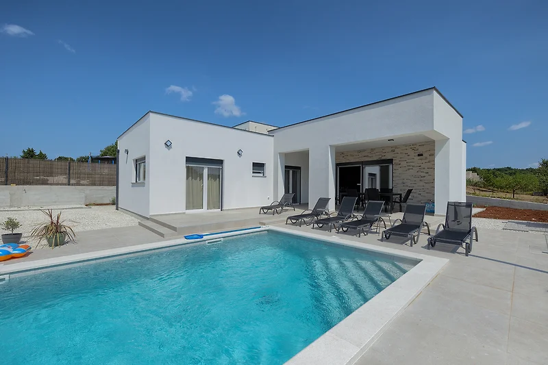 Villa mit Pool und Fliesen, umgeben von Beton.