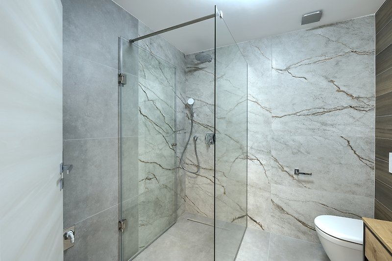 Modernes Badezimmer mit Dusche, Armatur und Glaswand.