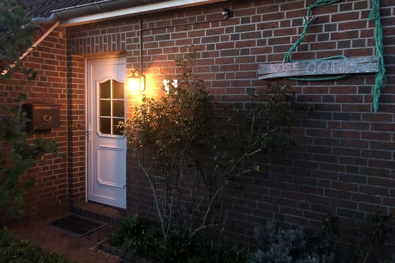 Gemütliches Haus mit schönem Garten und beleuchtetem Eingang.