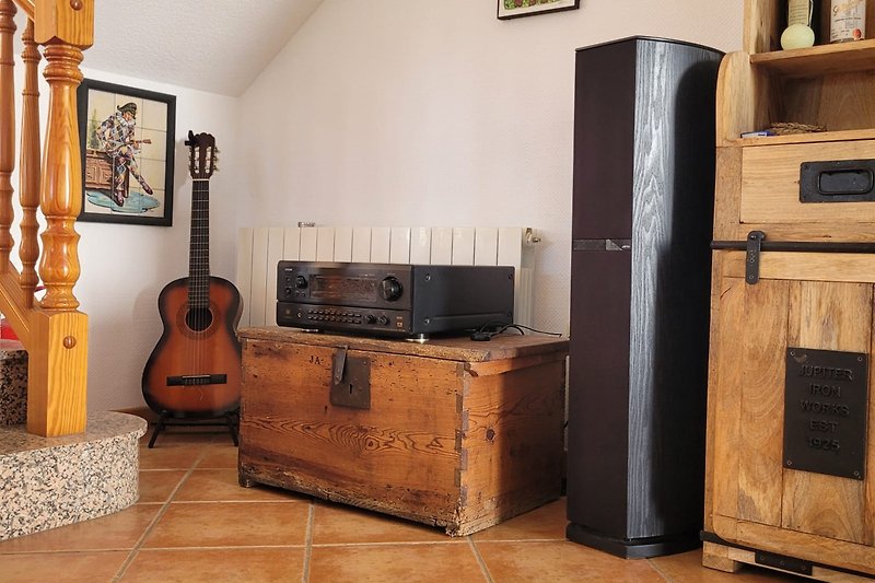 Gemütliches Wohnzimmer mit Holzmöbeln und musikalischen Instrumenten.