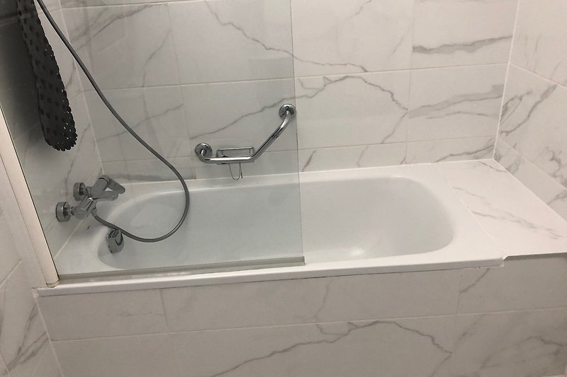 Ein stilvolles Badezimmer mit Badewanne, Dusche und elegantem Fliesenboden.