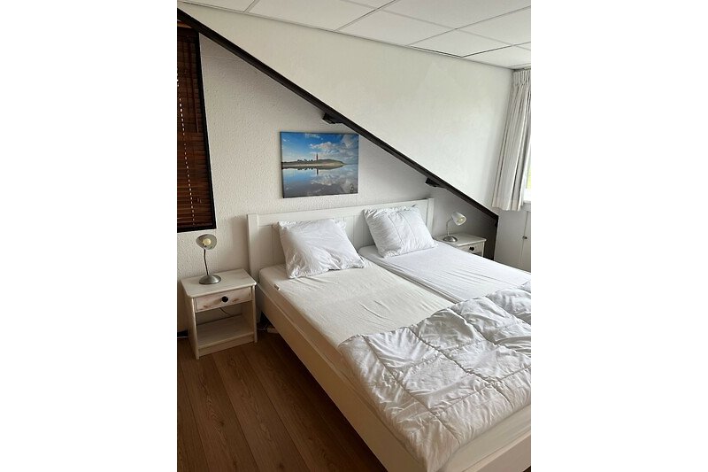 Slaapkamer met tweepersoonsbed en kastruimte op de etage