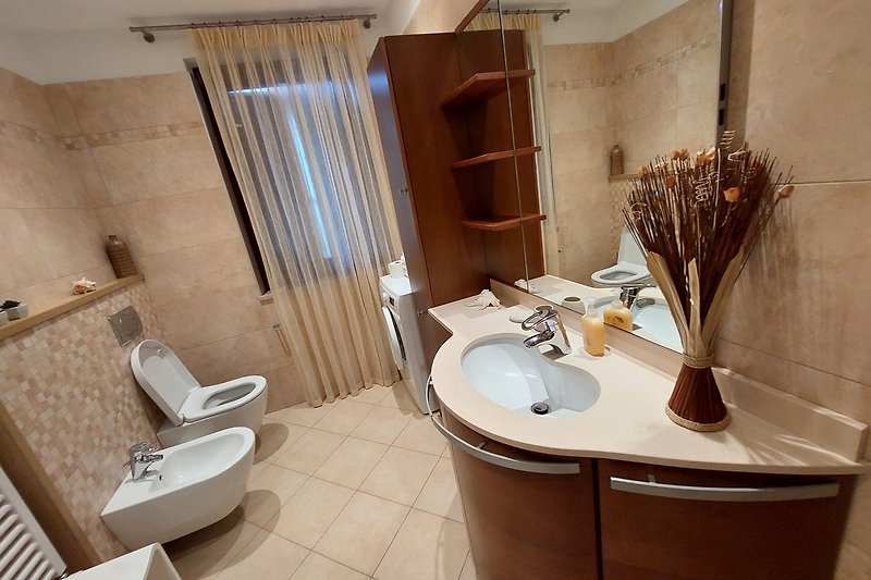 Un bagno moderno con lavandino, specchio e lavatrice