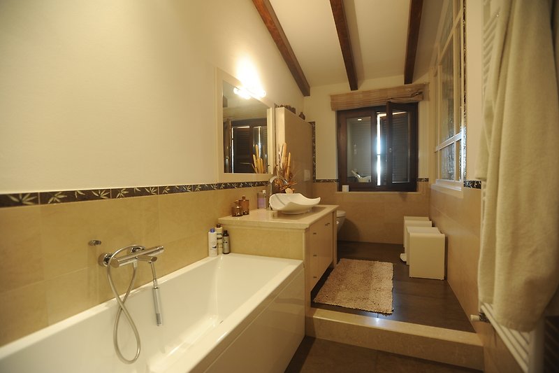 Un bagno elegante con specchio, lavandino e vasca da bagno.