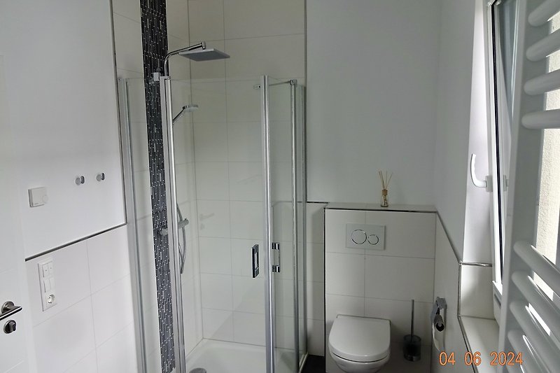 Bad OG mit elegantem Waschbecken, Toilette, Spiegel, Fenster und Raindancedusche