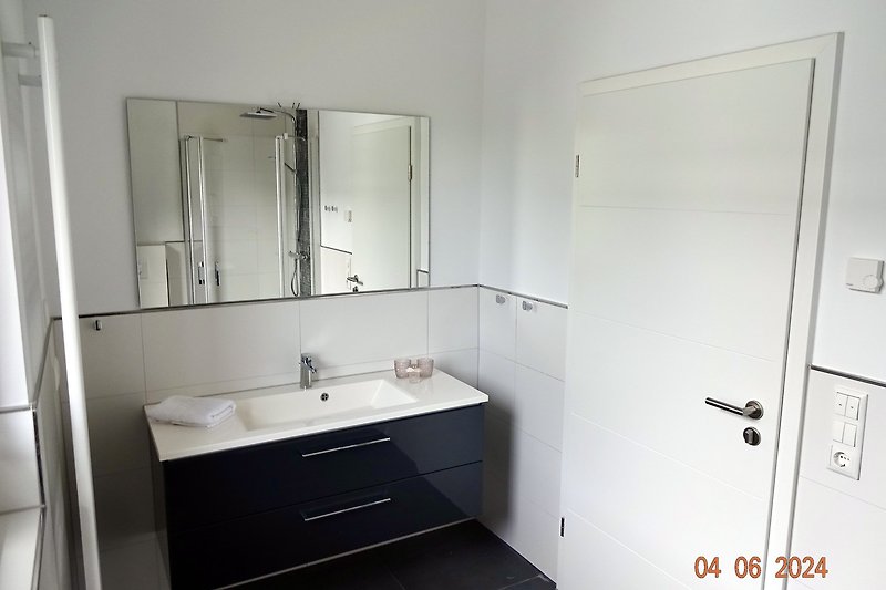 Bad OG mit elegantem Waschbecken, Toilette, Spiegel, Fenster und Raindancedusche
