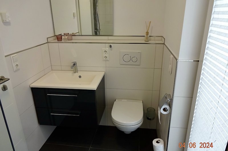 Bad EG mit elegantem Waschbecken, Toilette, Spiegel, Fenster und Raindancedusche