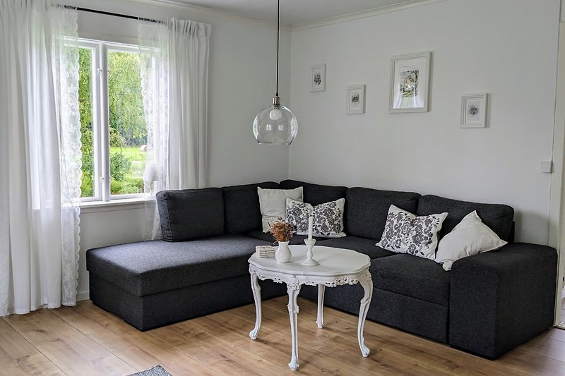 Gemütliches Wohnzimmer mit weißem Holzboden und bequemer Couch.