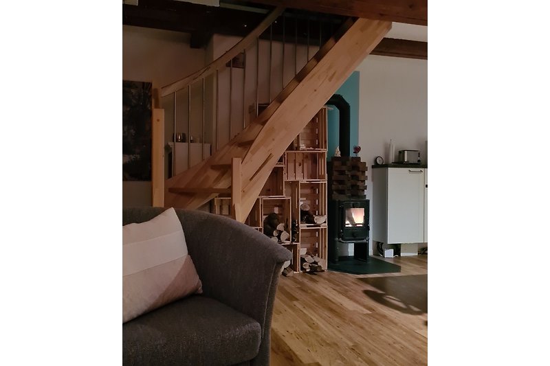 Kamin im Wohnzimmer – die Holztreppe führt zum Schlaf- und Wohnbereich auf der 2. Ebene mit Meerblick