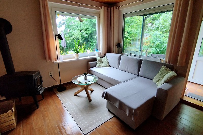 Gemütliches Wohnzimmer mit bequemer Couch, Tisch und Fenster. Entspannen Sie sich und genießen Sie den Komfort.