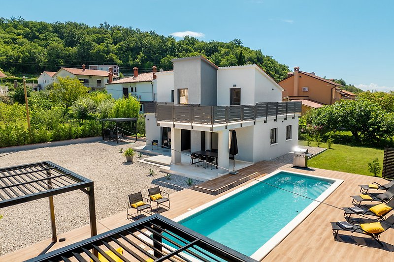 Villa mit Pool, Sonnenliegen und üppiger Gartenlandschaft.