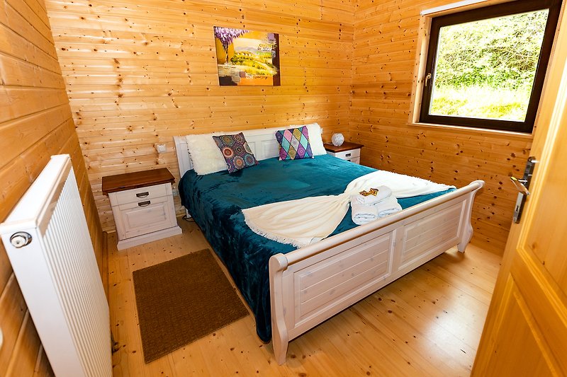 Gemütliches Schlafzimmer mit Holzbett, Fenster und gemütlicher Einrichtung.