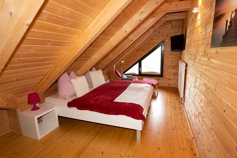 Gemütliches Schlafzimmer mit Holzboden, Fenster und bequemem Bett.