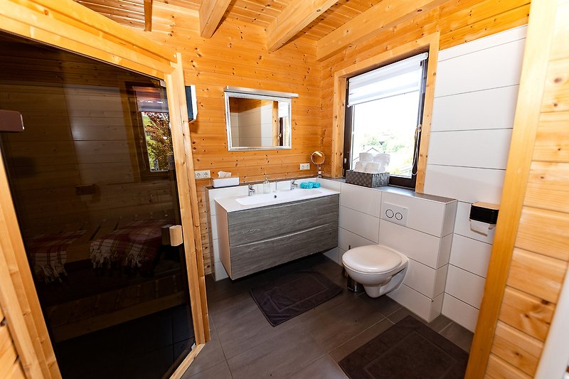 Ein stilvolles Badezimmer mit Holzboden, Fenster und modernen Armaturen.