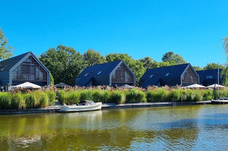 Ferienhaus am See mit Booten, grüner Landschaft und idyllischem Garten.