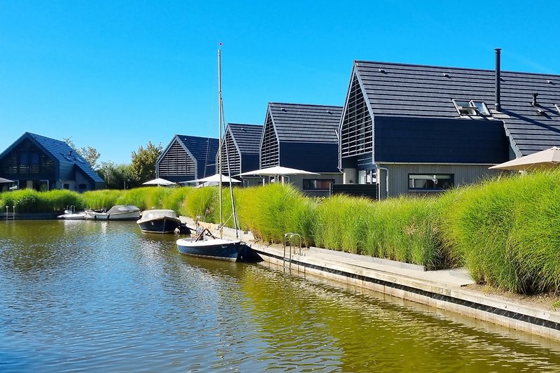 Ferienhaus am See mit Booten, grüner Landschaft und schöner Aussicht.
