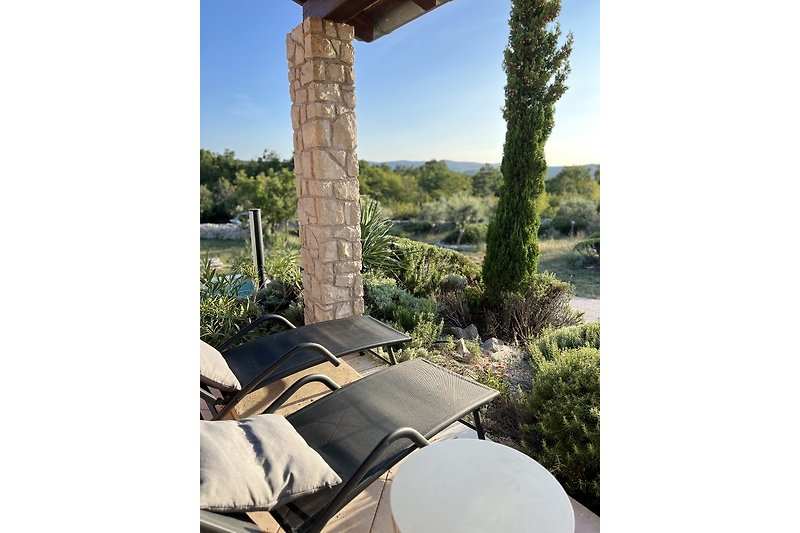 Einladende Terrasse mit bequemen Möbeln und grüner Pflanzenlandschaft.