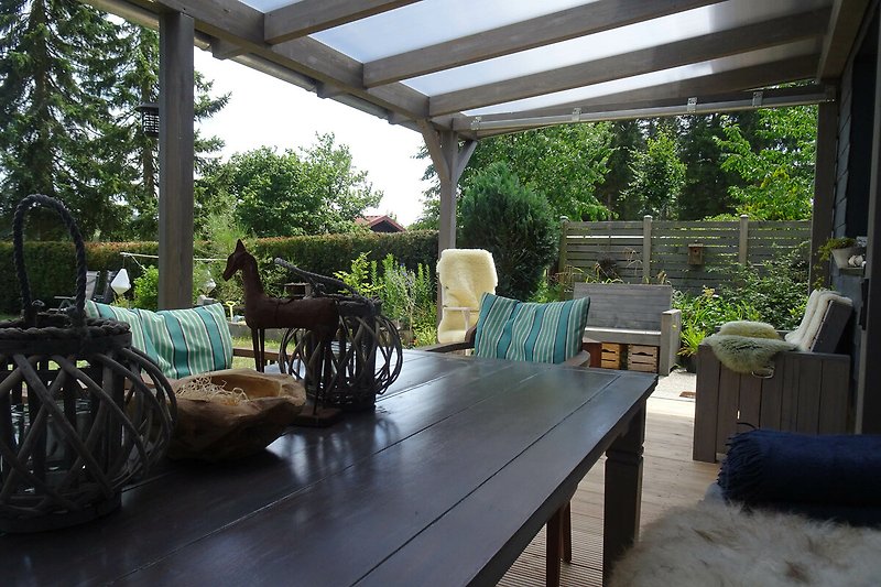 Gemütliches Cottage mit überdachter Terrasse und Holzmöbeln. Perfekt zum Entspannen in der Natur.