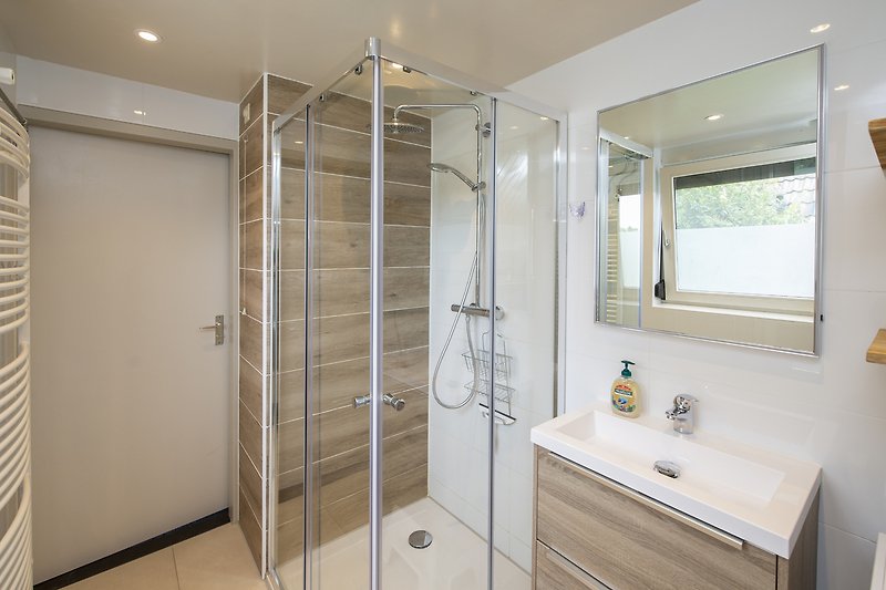 Modernes Badezimmer mit Regendusche, Spiegel und Waschbecken.