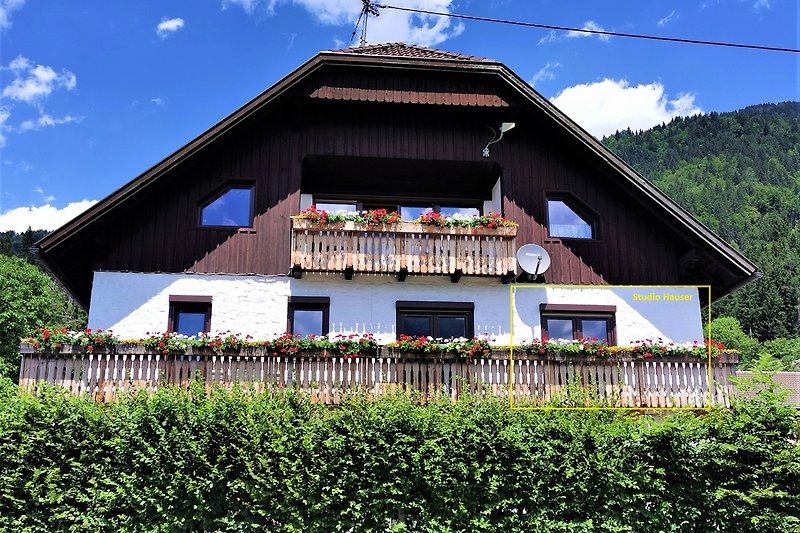 Traditionelles Haus mit Holzfassade, umgeben von grüner Landschaft.